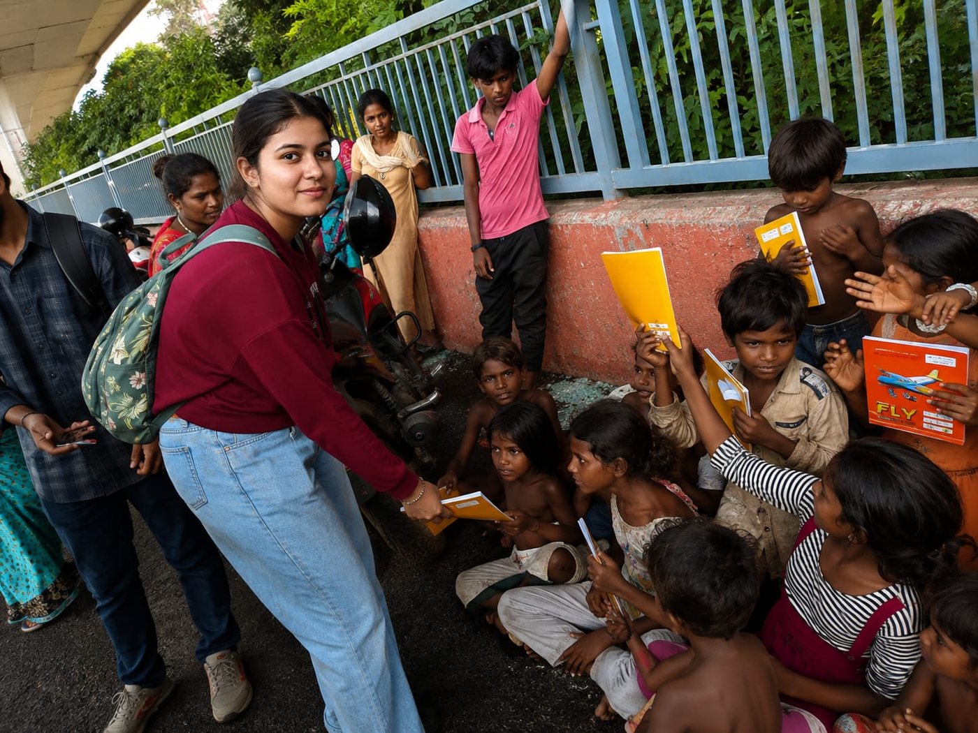 An HCF member handing notebooks to children near E-Block, Patna